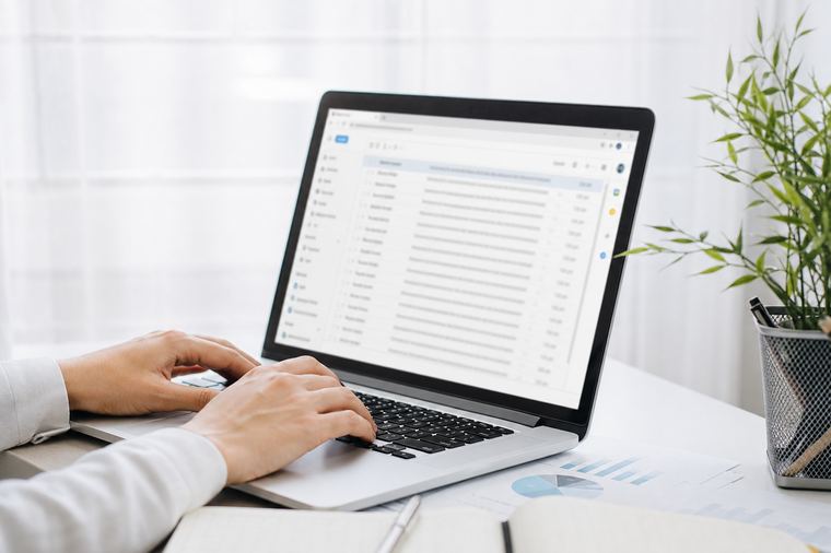 Professionista al portatile mentre apre l'allegato di una notifica ricevuta via posta certificata